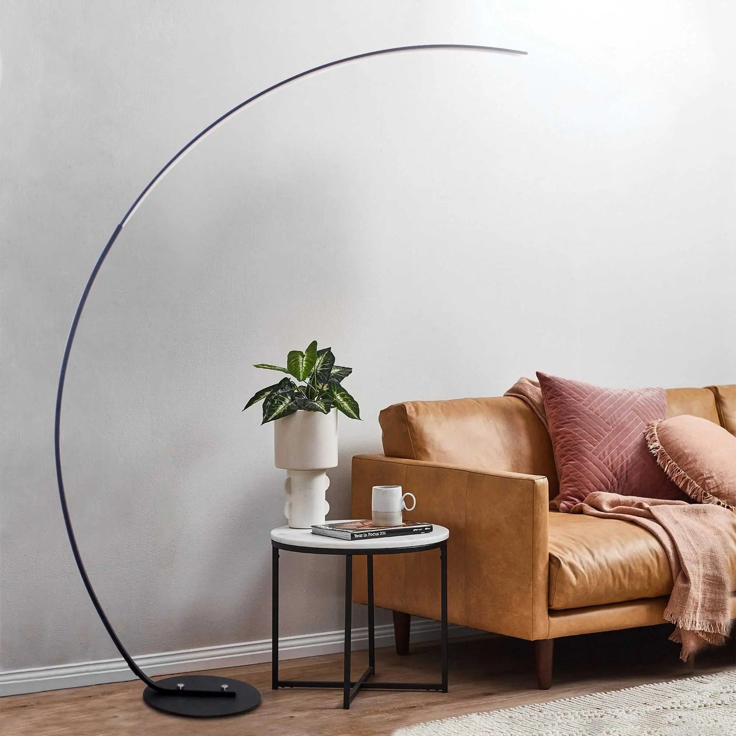 Black RGBW modern curve floor lamp with metal and aluminum design beside brown leather sofa in living room