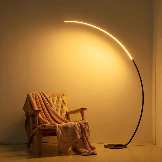 RGBW modern curve floor lamp with warm LED light beside wooden chair with blanket in cozy room