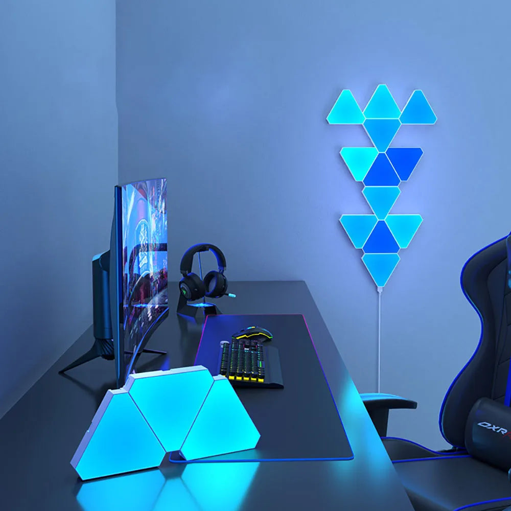 LED Triangular Quantum Lamp glowing blue on bedroom wall with gaming desk setup including monitor, keyboard, and headphones