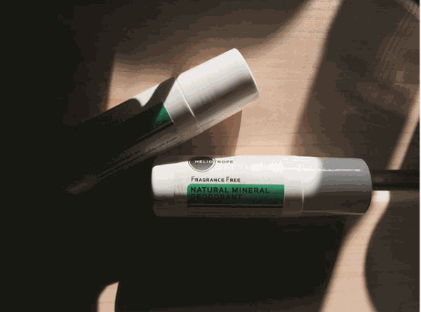 Natural Mineral Deodorant fragrance-free roll-on bottles on wooden surface with sunlight and shadow