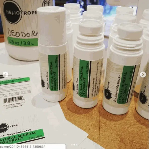 Natural Mineral Deodorant roll-on sticks in various essential oil scents on a wooden surface with refill container in background