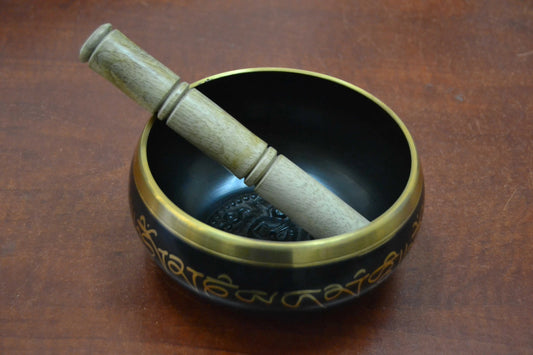 Handmade Nepal Tibetan brass singing bowl with wooden striker on wooden surface