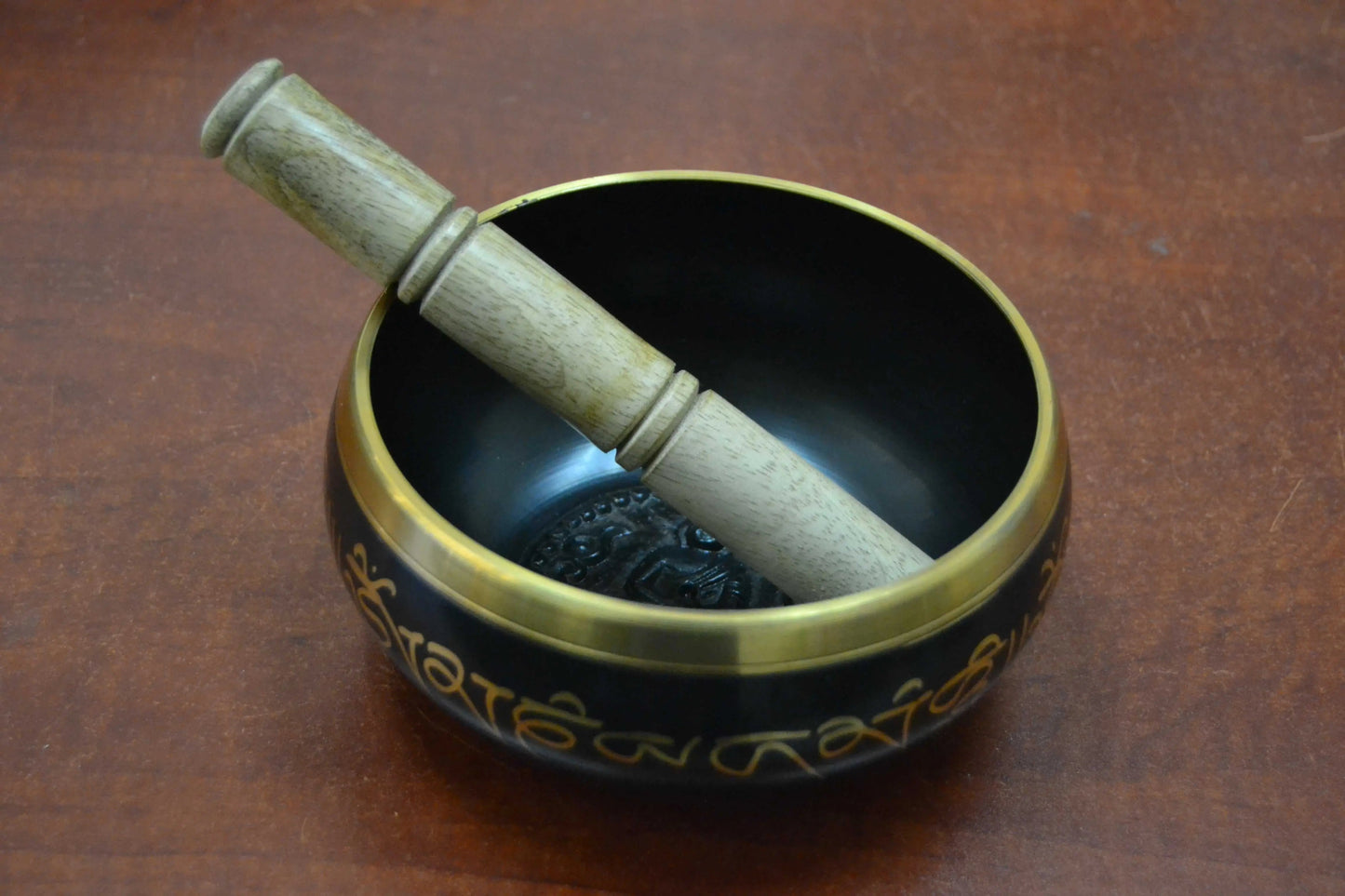 Handmade Nepal Tibetan brass singing bowl with wooden striker on wooden surface