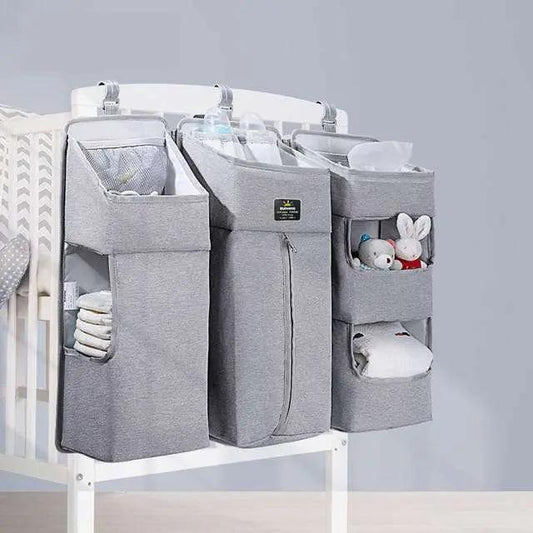 Gray Baby Diaper Caddy with multiple compartments hanging on crib side for organized baby essentials storage