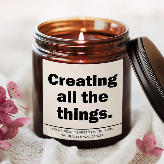 Creating all the things Candle in amber jar with lit wick and eco-friendly soy wax blend