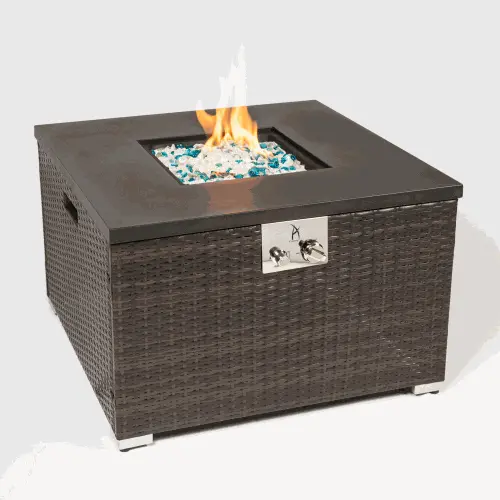Outdoor gas fire pit table with dark brown wicker body and steel tabletop burning blue and clear glass rocks