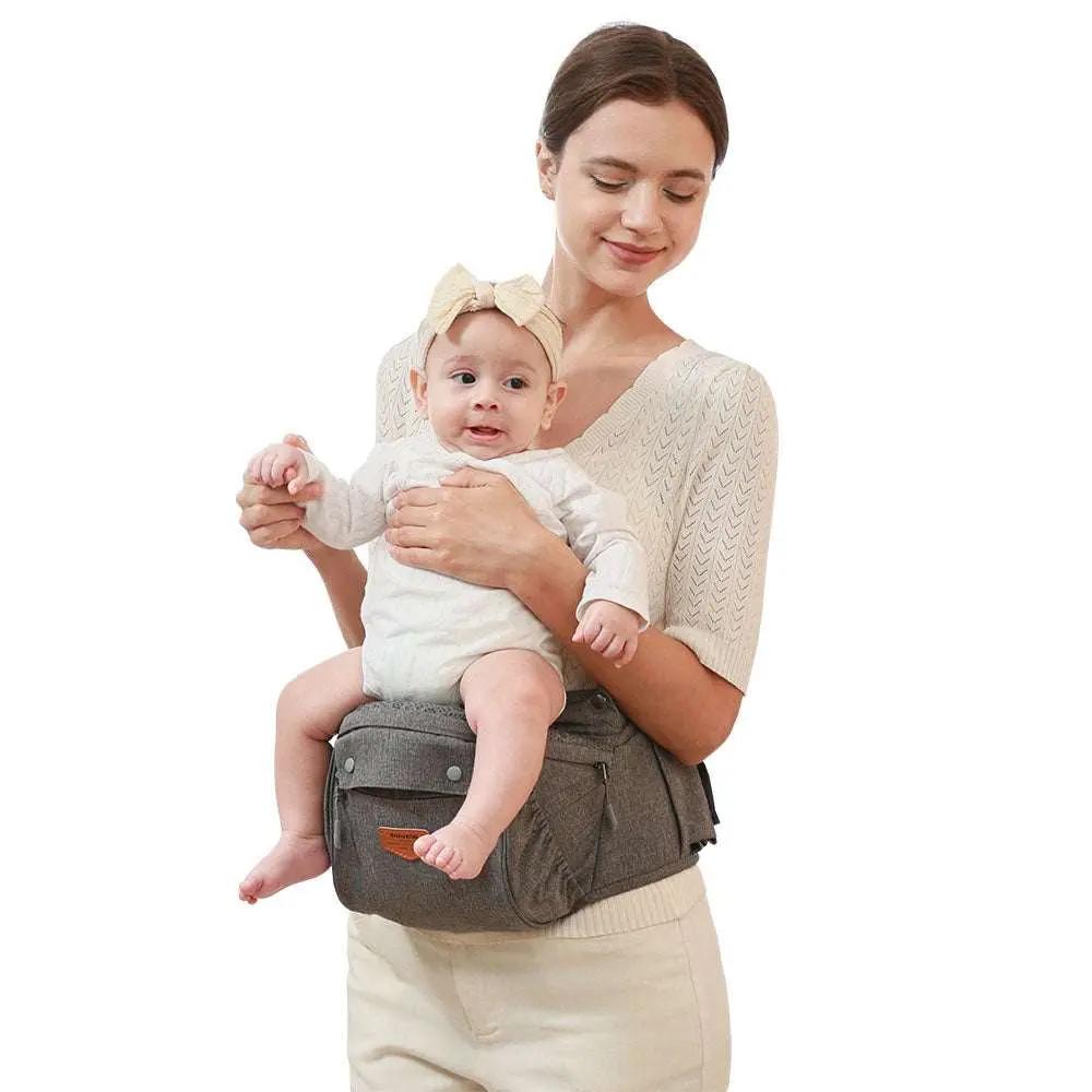 Mother carrying baby in ergonomic baby carrier with hip seat in gray color