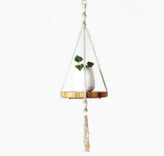 Handcrafted ecru cotton macrame plant hanger with wooden tray holding a small white vase with green leaves