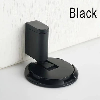 Black windproof door stopper installed on floor against wall to hold door open