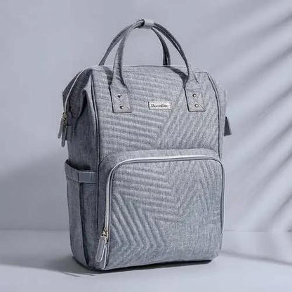 Gray quilted diaper bag backpack with multiple pockets and padded handles for parents on the go