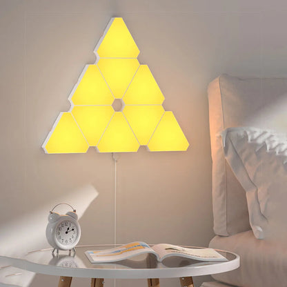 LED Triangular Quantum Lamp glowing yellow mounted on bedroom wall above bedside table with alarm clock and book