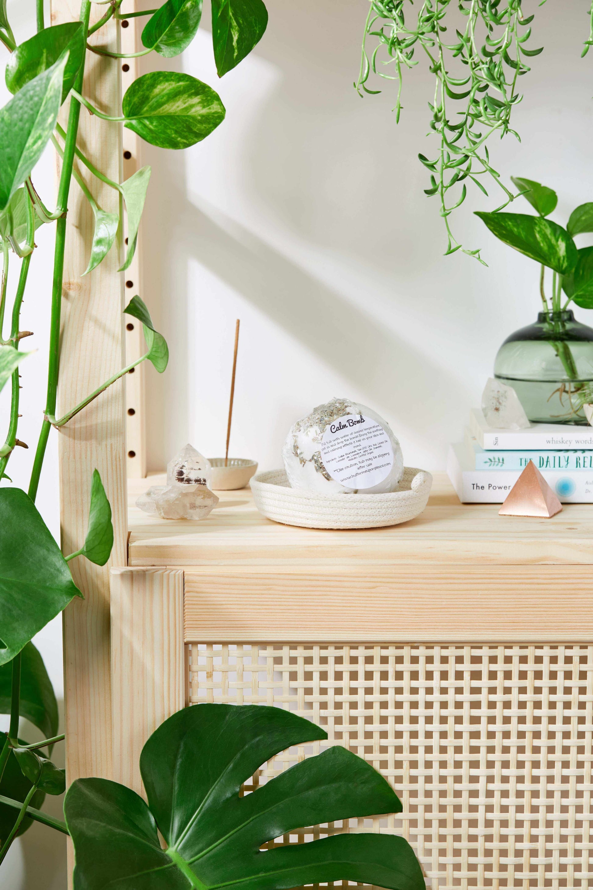 Organic bath bomb Calm Bomb with lavender on wooden shelf surrounded by green plants