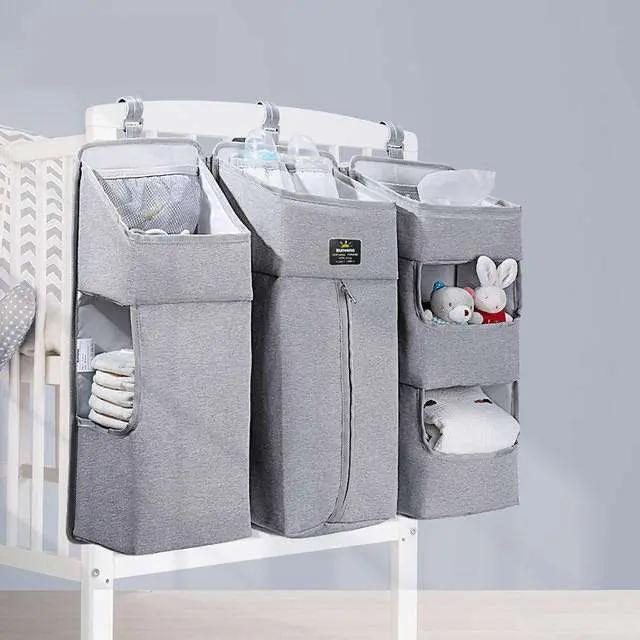 Gray Baby Diaper Caddy with multiple compartments hanging on crib side for organized baby essentials storage