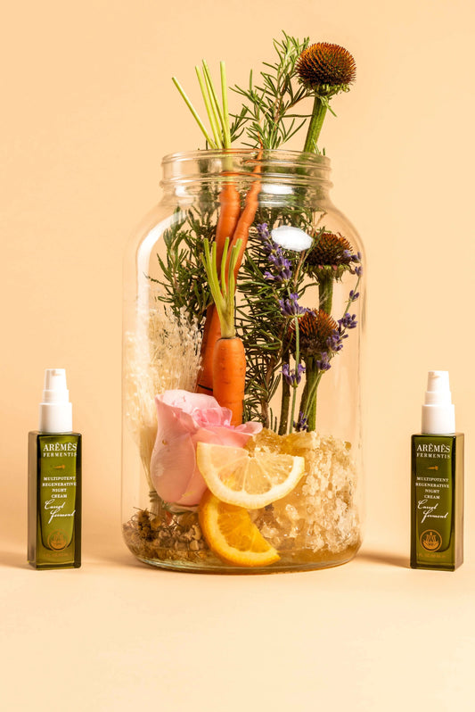 Multipotent Regenerative Night Cream with natural botanical ingredients and antioxidants displayed with fresh carrot, herbs, and citrus slices in jar
