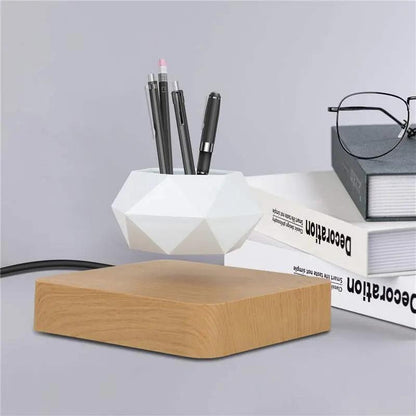 Levitating rotation flowerpot with magnetic floating white geometric pot on wooden base next to books and glasses