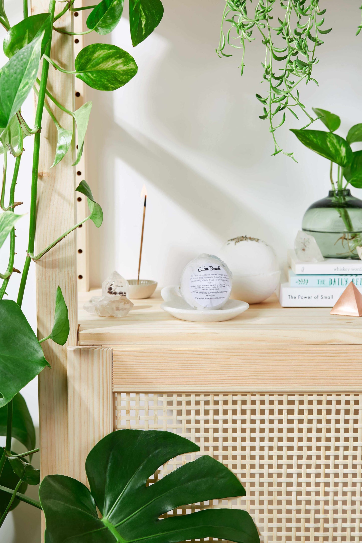 Organic Bath Bomb Calm Bomb with lavender on wooden shelf surrounded by green plants and books